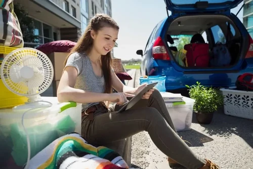 College student sitting outside with belongings